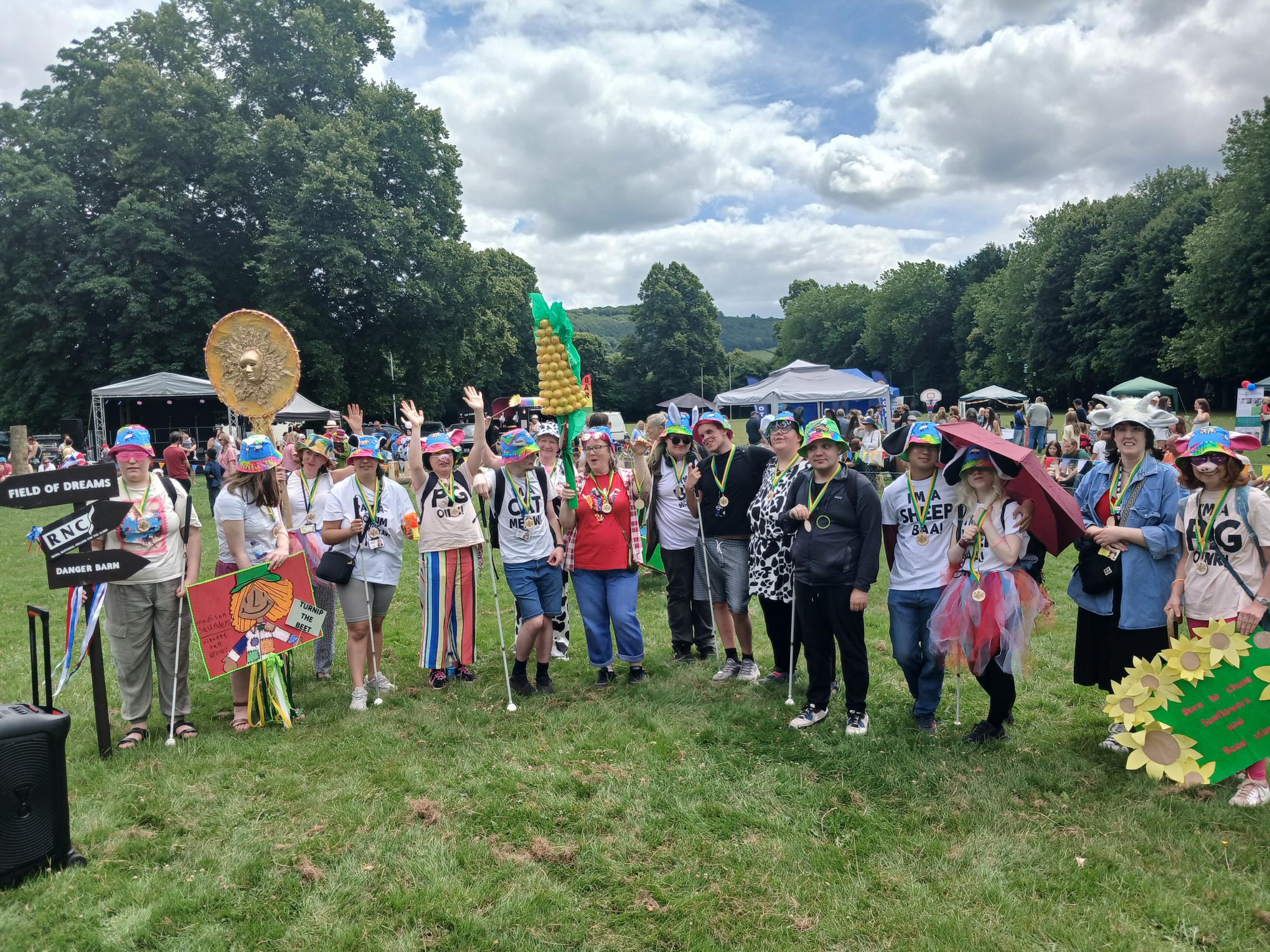 The full group in colourful hats and tshirts with animal ears, snouts and whiskers. They're all cheering and wearing their winners medals
